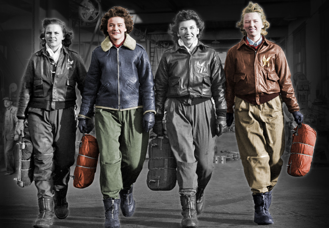 Women in flight suits walking on an airplane manufacturing shop floor.