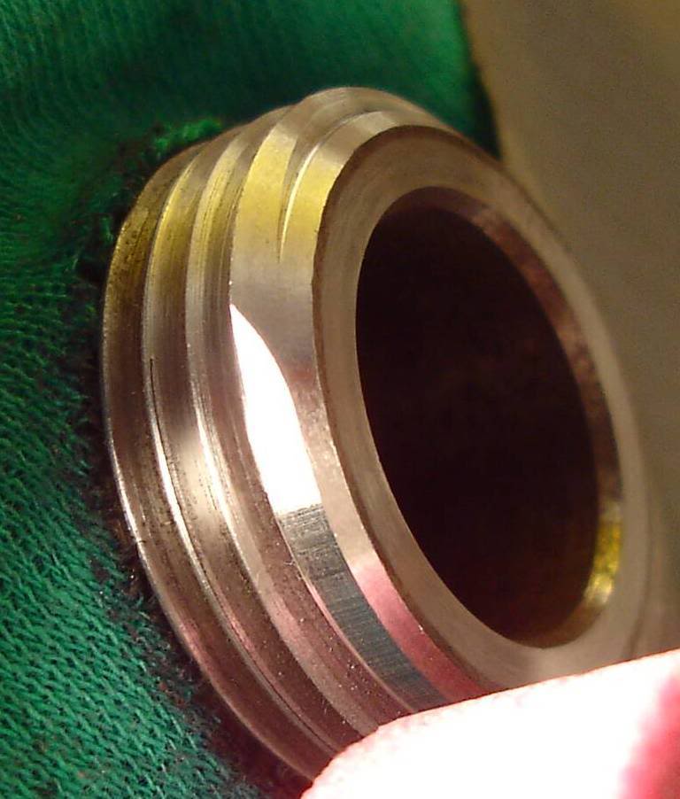 Silver-colored metal object with hole, attached to green fabric.