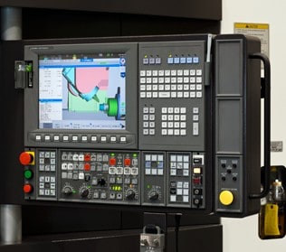 Control panel of an industrial machine with a digital screen displaying graphs, various buttons, and dials.