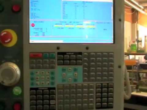 Industrial control panel with a keyboard and display screen showing data, situated in a factory setting.