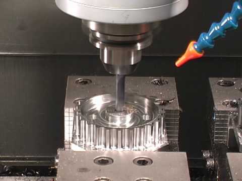 A cnc machine milling a metal part with a cooling fluid nozzle applying lubricant, focused on the tool and workpiece.