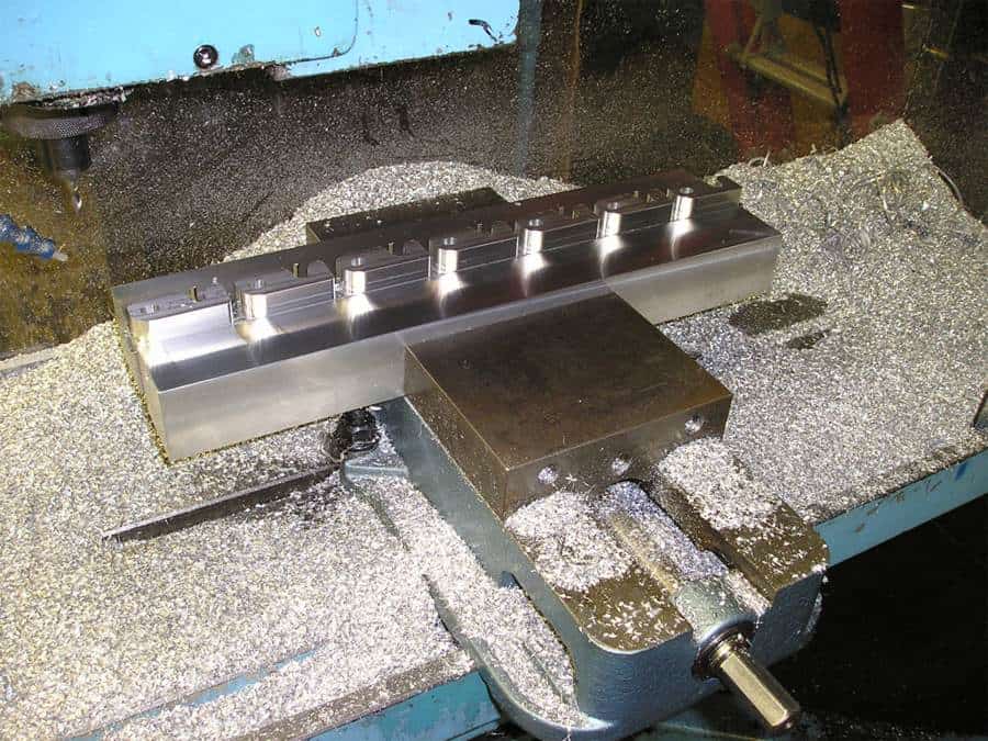 A machinist is using a machine with a machinist vise to craft a piece of metal.