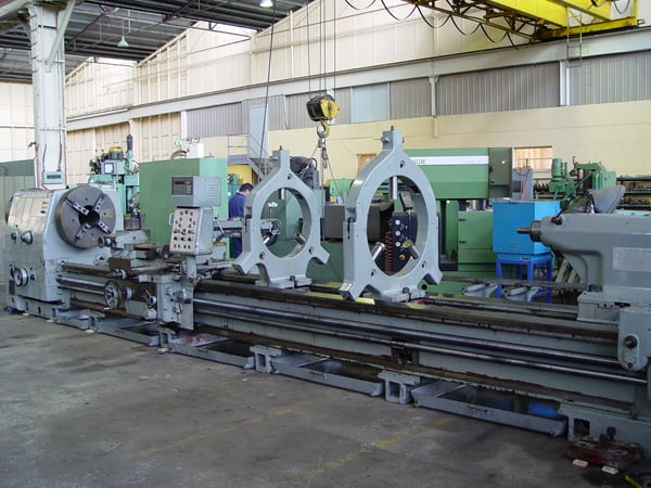 Industrial facility with a row of metalworking lathe machines under bright factory lights.