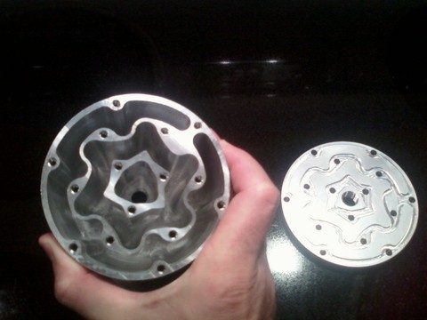 Round metal component with deep pockets and holes.