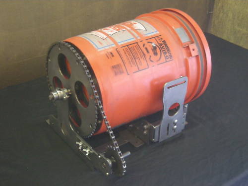 Orange cylinder with black interior, chained, on dark gray surface against brown background.