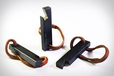 Steel bottle opener with black finish and leather strap attachment.