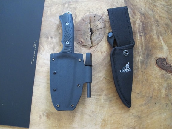 Two knives with Kydex sheathes on a wooden table next to each other.