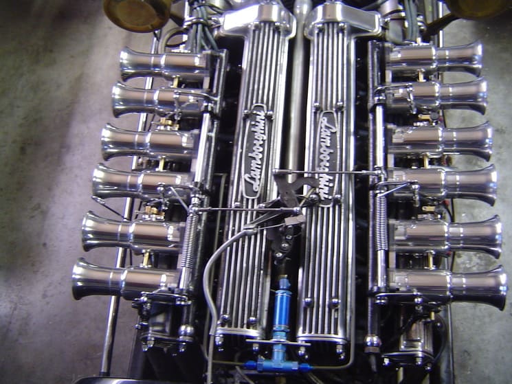 A Lamborghini engine block with eight exhaust pipes protruding from the top.