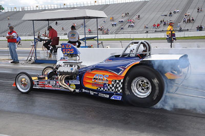 A man experiencing intense acceleration while driving a drag car with smoke coming out of it.