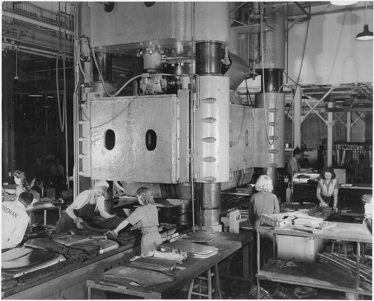 A black and white photo of people managing in a factory.