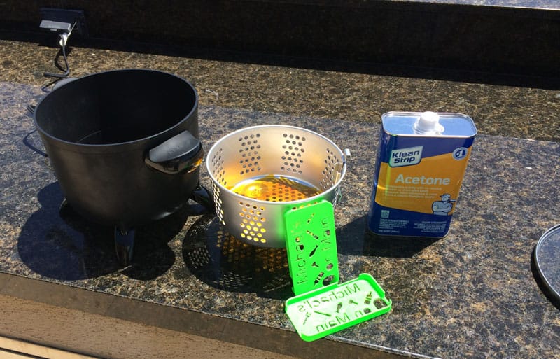 A bucket containing a bottle of water and a few 3D printed parts is placed on the counter top.