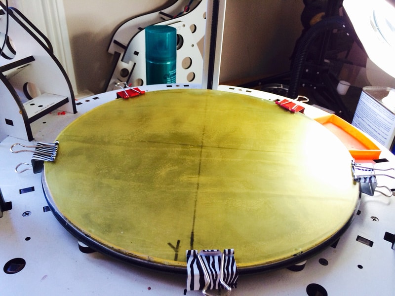 A gold plate getting printed on a table in a room using 3D printing technology.