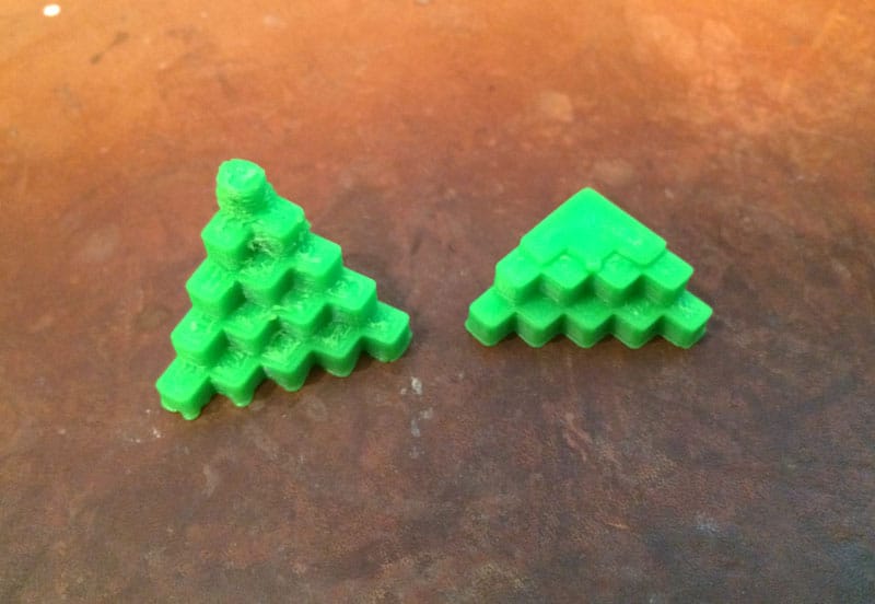 Two green plastic Christmas trees on a table undergoing a tuneup.