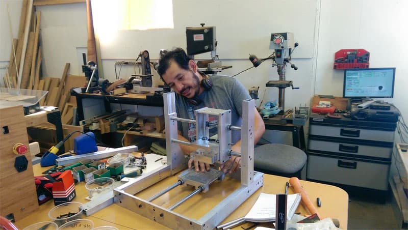 A man operating a Nomad CNC Mill in a Carbide LLC workshop.