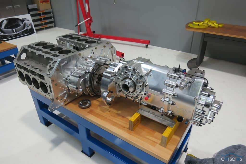 Large metal engine block on a wooden workbench in an industrial workshop setting.