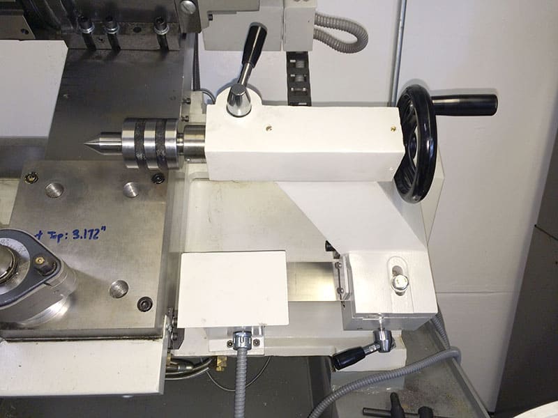 White lathe tool with black handle and metal base plate with inch measurements.