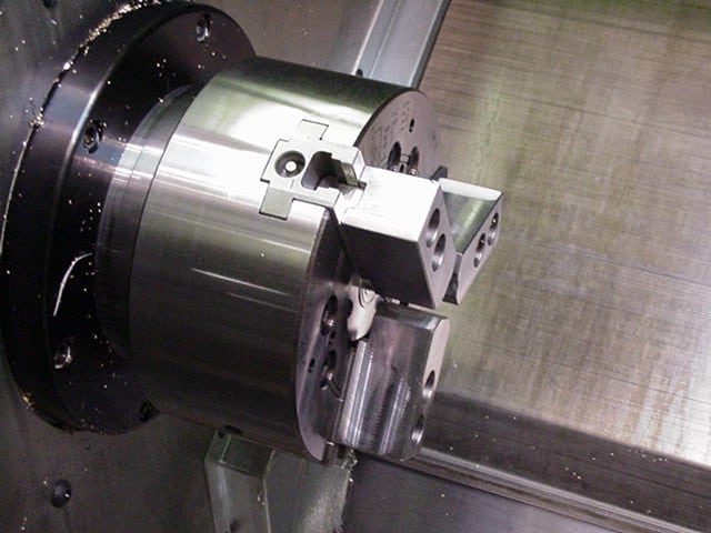 A cnc milling machine with a metal part on it, using workholding for precision machining.