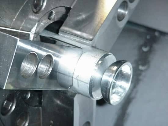 Metal object with cylindrical shape and flat top, featuring holes or grooves on its surface, made from shiny metallic material such as aluminum or steel.