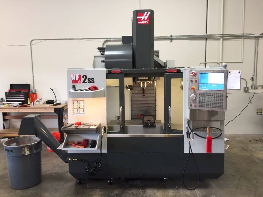 A Haas VF2-21 vertical machining center (VMC) in a well-lit workshop, showcasing its advanced features and capabilities.