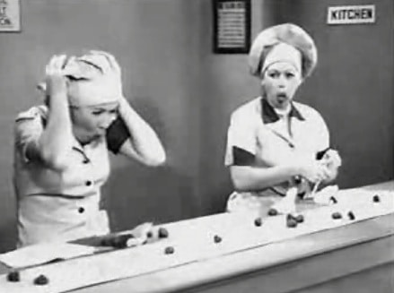Two women in a kitchen, one in an apron, the other wearing a chef's hat.