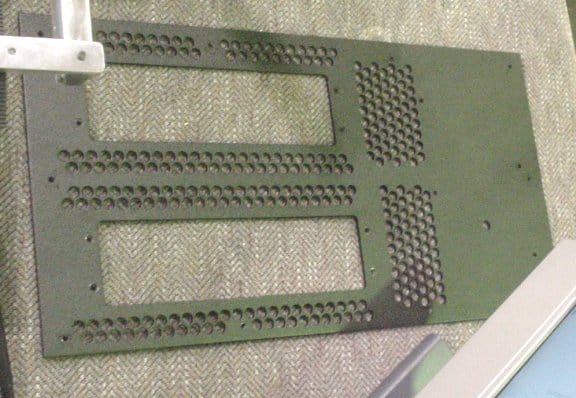 Metal plate with evenly spaced holes on each side.