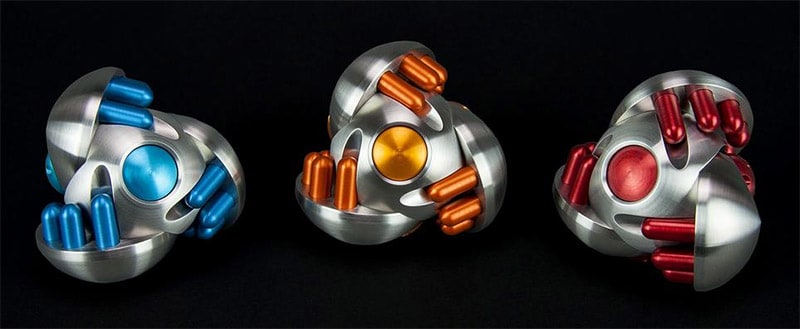 Silver machine part with rounded edges and colored cylindrical protrusions.