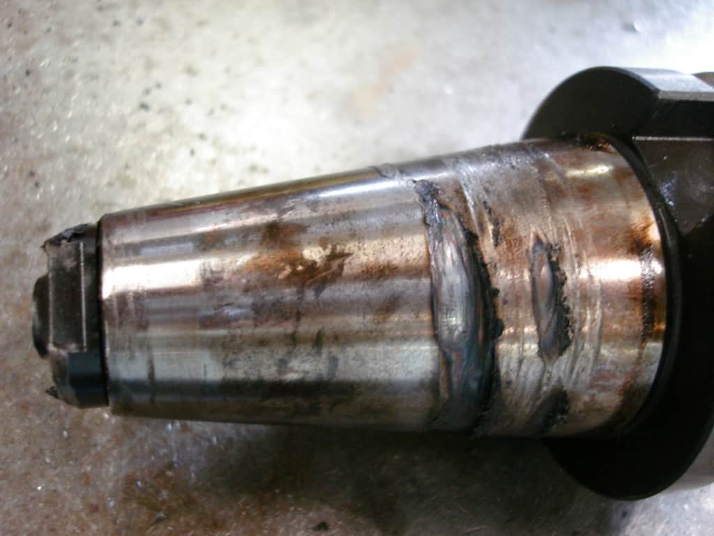 Cylindrical metal object with conical end and signs of wear and rust.