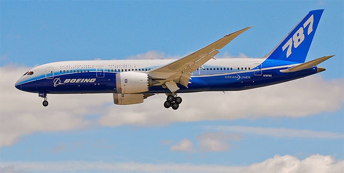 A blue and white airplane soaring in the sky, fabricated using carbon fiber machining.