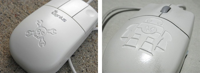 An engraved computer mouse featuring a skull and crossbones on its irregular surface.