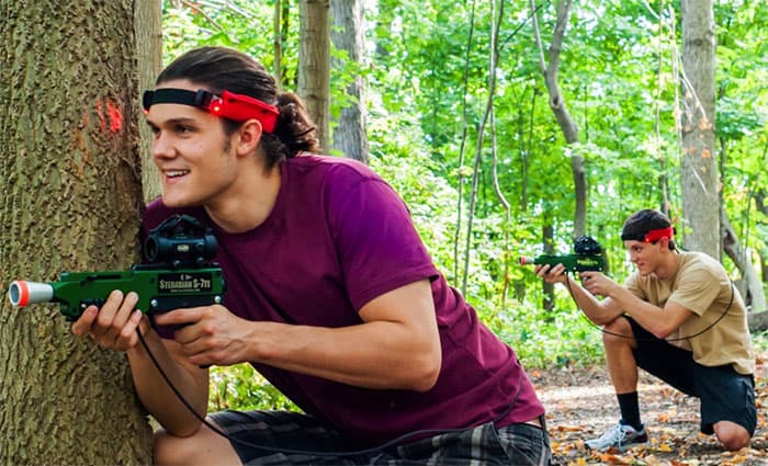 Two young men playing paintball in the woods, showcasing Steradian Tech.