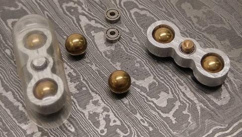 A fun fidget spinner with gold balls amidst CNC gifts on a table.