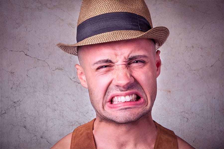 A man in a hat with his mouth open, using a Tramp Oil Skimmer.