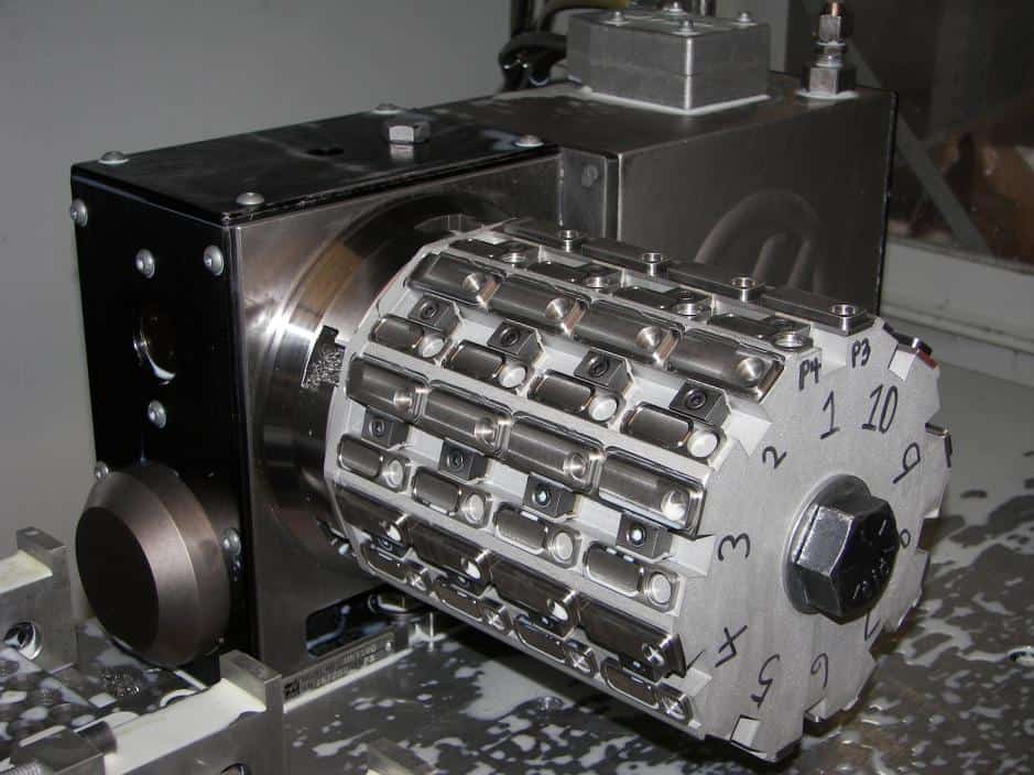 Metal fixture with cylindrical component and small metal pieces on workbench.