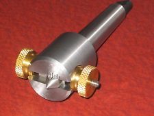 Silver metal tool with brass knobs and tapered shape.