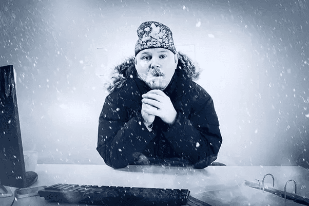 A man sitting in front of a computer with snow falling around him, working on advertising strategies for cold emails.