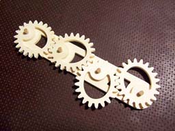 Gear-like object with a smiley face carved into it, on a brown background.