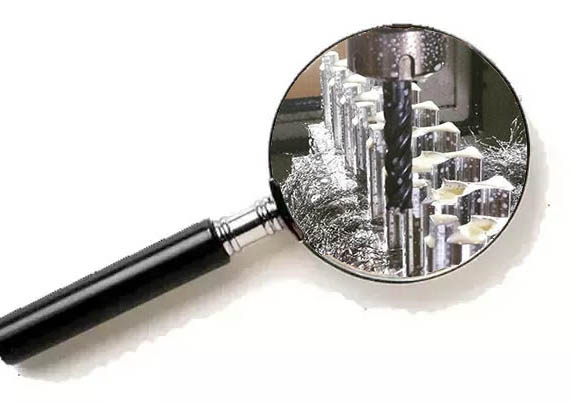 Magnifying glass with drill bits and cutting tools.
