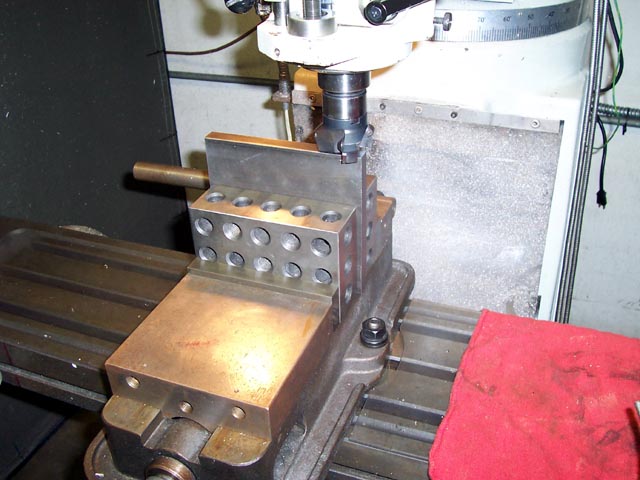 Large brass or bronze metal plate on milling machine table with vice holding it in place.
