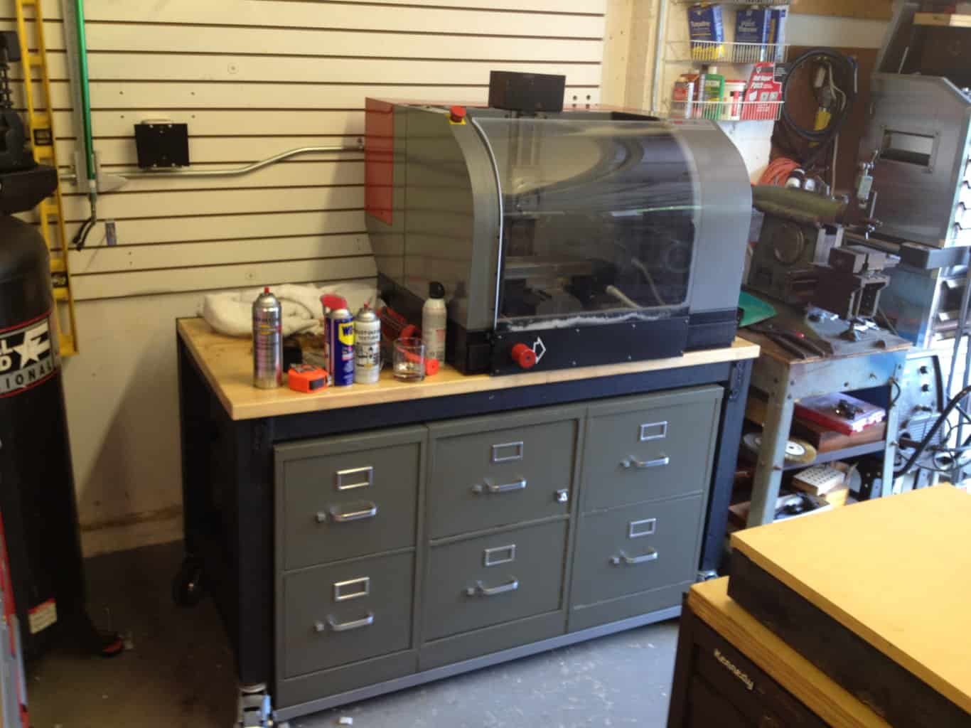 Well-organized metal workshop with gray cabinet and tools on workbench.