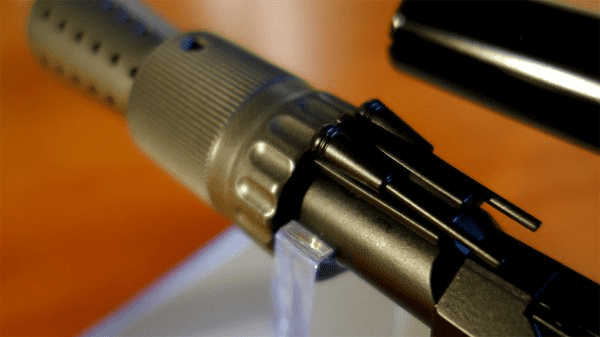 Metal rod with threaded tip and small holes, on an orange surface.