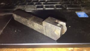 A close-up photo of a rectangular metal object with a small hole and flat top surface.