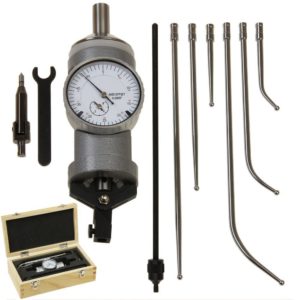 Precision instruments and tools in a machine shop or metrology setting, including a large round device with attachments and accessories.