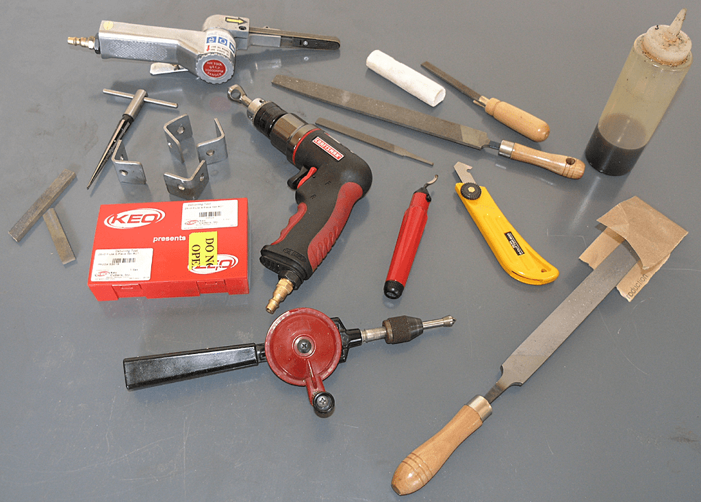 A variety of deburring tools for metal are laid out on a table.