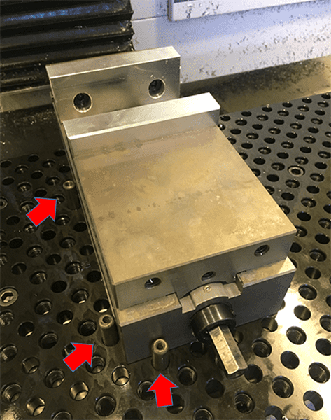 Metal object with holes on black grid-like surface.