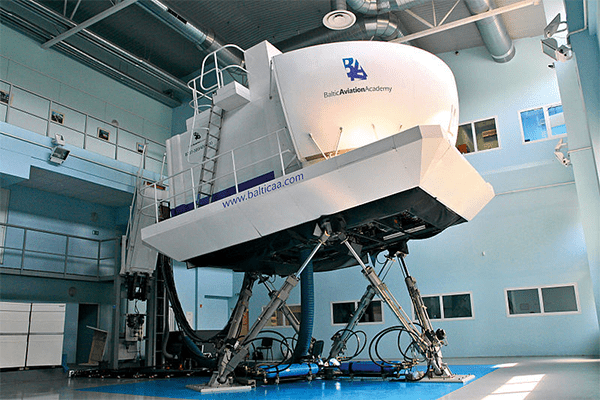 White flight simulator with blue logo and control panel in a light blue walled room.