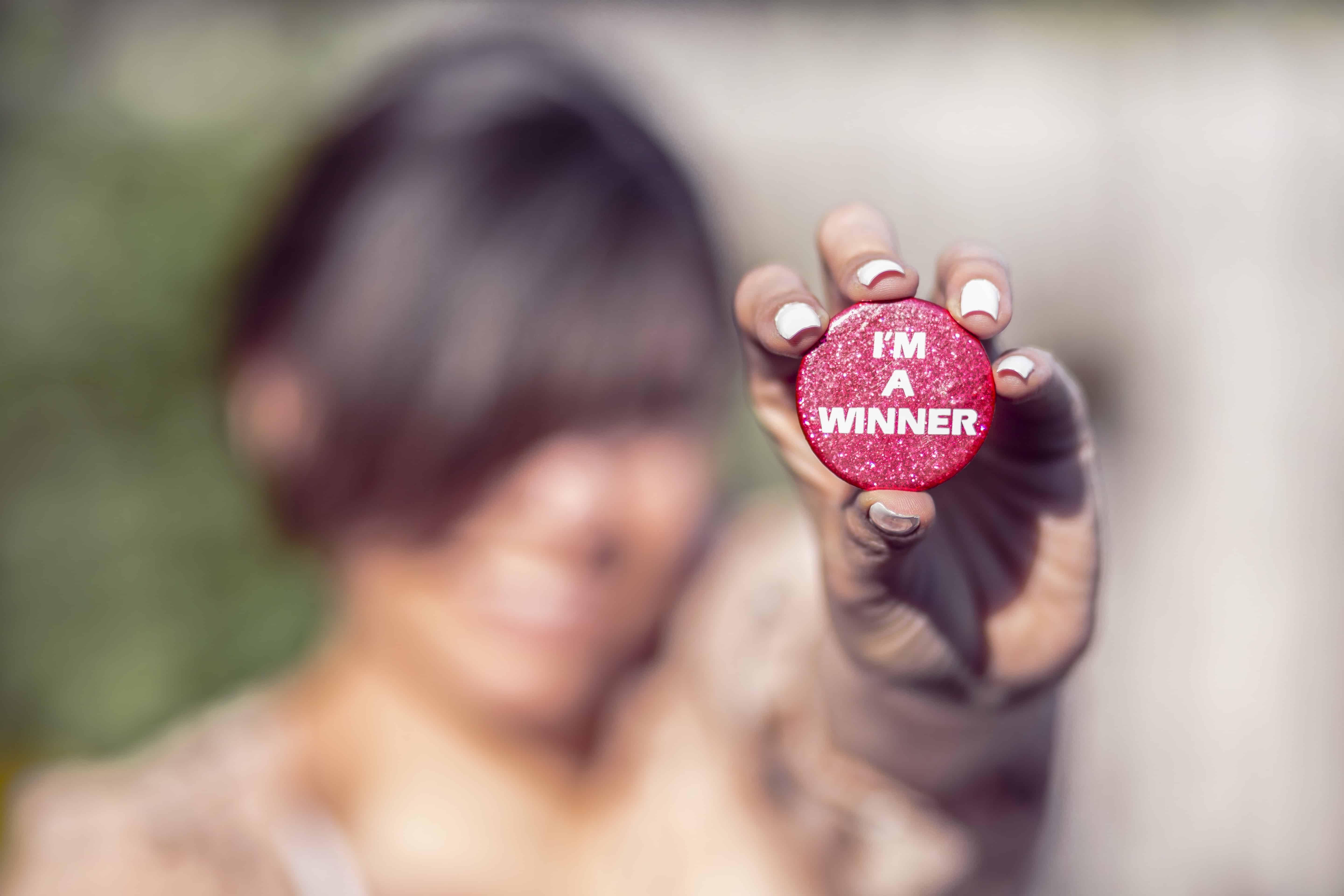 A woman proudly displaying a button that says "I'm a winner".