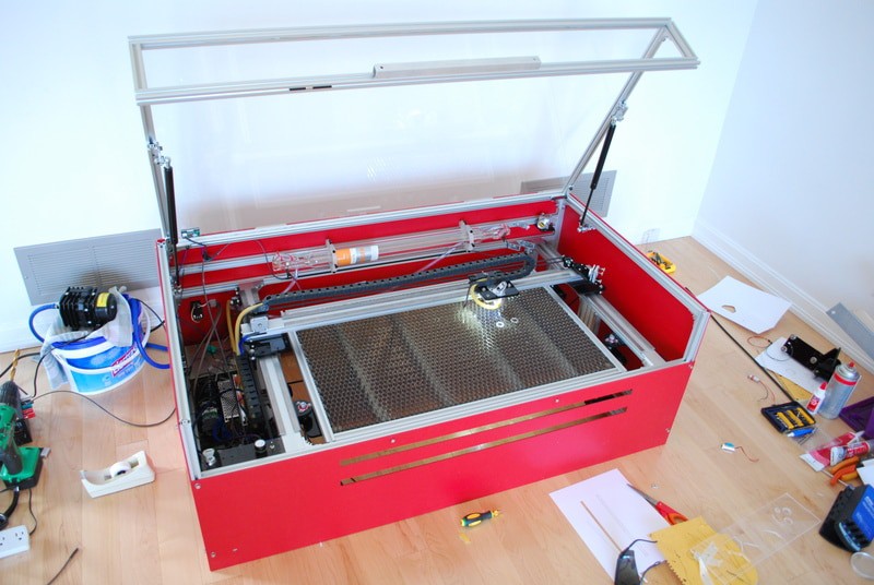 A red laser engraver with surrounding tools and equipment.