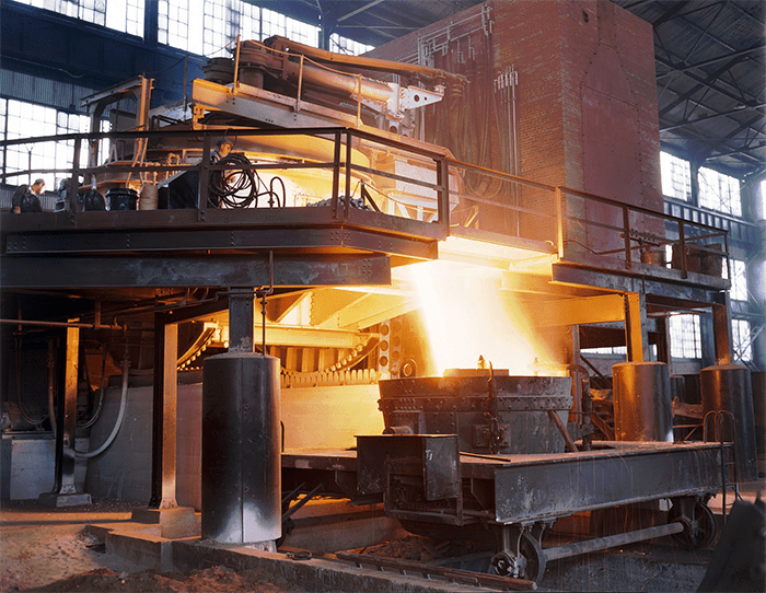Industrial furnace with fiery glow in a cluttered workshop setting.