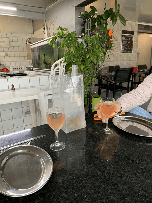 A restaurant kitchen with a person at the counter holding a glass of wine.