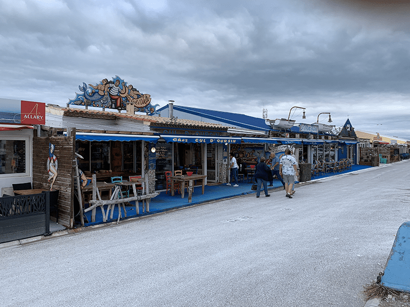 Weathered wooden building with blue awning and red sign "Allary".